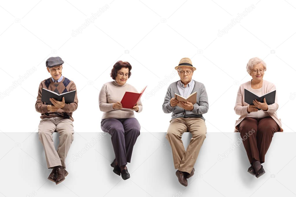 Group of elderly people sitting on a white panel reading books