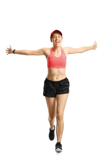 Молодая улыбающаяся женщина в спортивной одежде бегает и расправляет руки — стоковое фото