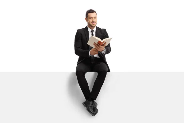 Бизнесмен, сидящий на баннере с книгой и смотрящий на c — стоковое фото