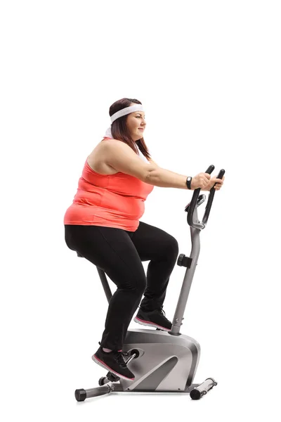 Corpulent woman exercising on a stationary bike — Stock Photo, Image