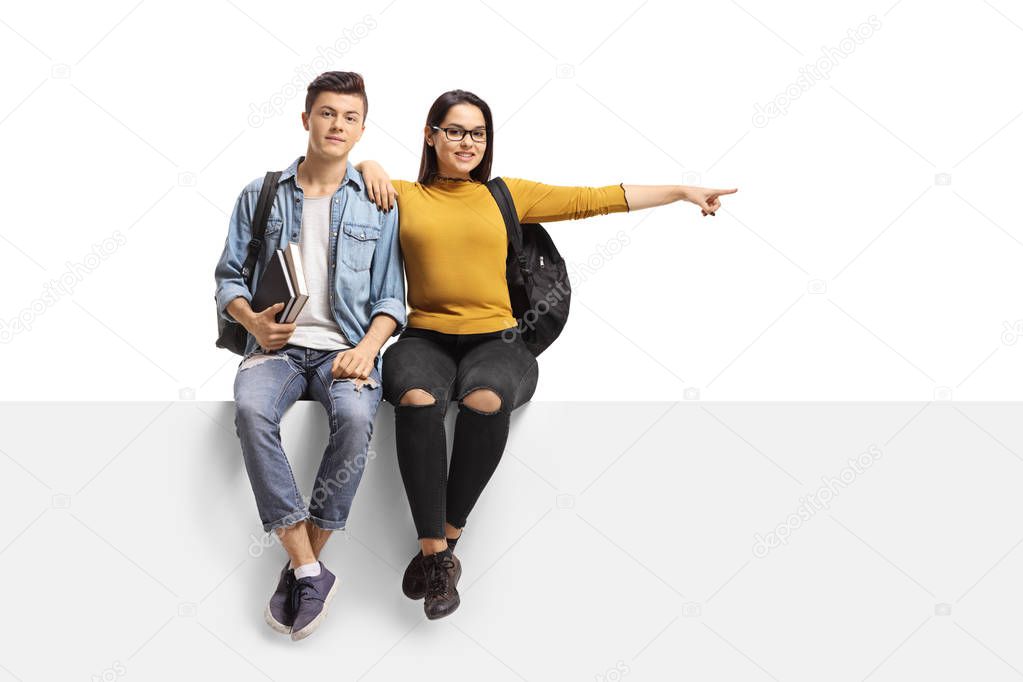 Male and female student sitting on a panel and pointing to the s