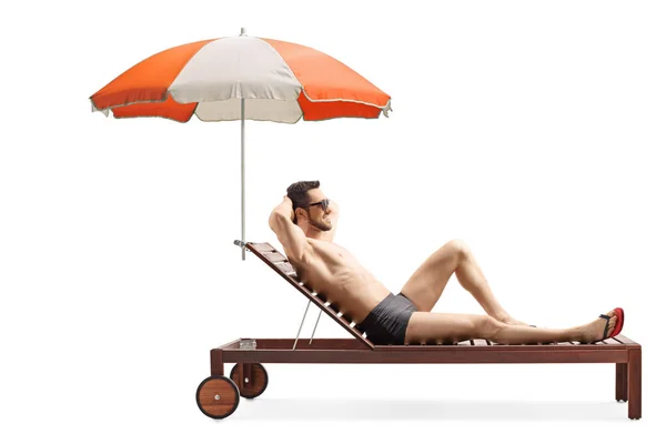 Bello uomo su un lettino sotto l'ombrello — Foto Stock
