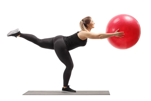 Mulher exercitando com uma bola de fitness e levantando uma perna — Fotografia de Stock