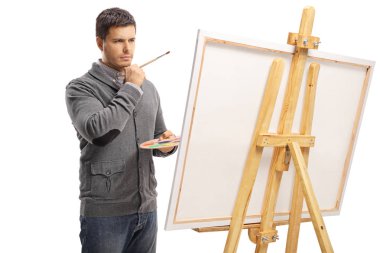 Bir fırça ile bir resim tuval önünde duran pensive adam 
