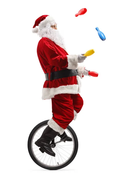 Święty Mikołaj jeździ unicycle i żonglerka z klubami — Zdjęcie stockowe