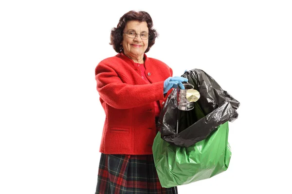 Mujer madura lanzando una lata en una bolsa de basura — Foto de Stock
