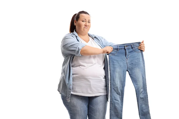 Mujer triste con sobrepeso sosteniendo un par de vaqueros pequeños —  Fotos de Stock