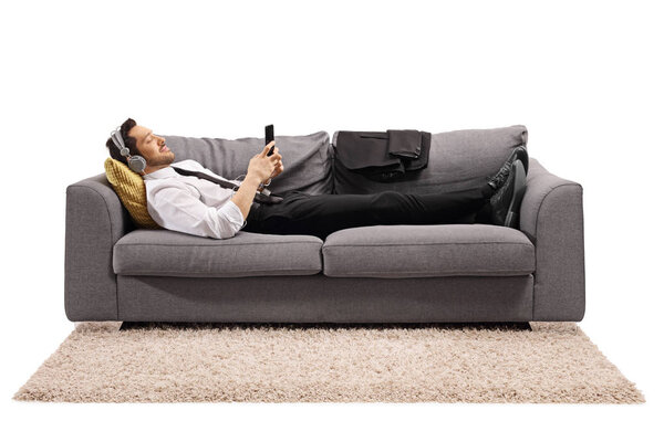 Businessman lying on a sofa and listening to music 