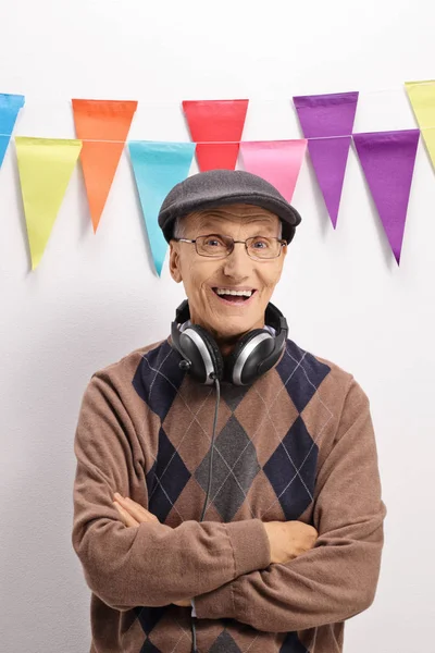 Mature man with headphones smiling against a wall