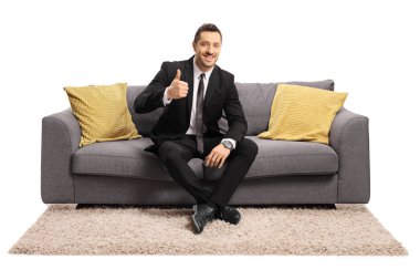 Neşeli genç işadamı kanepede oturan ve başparmak gösteren 