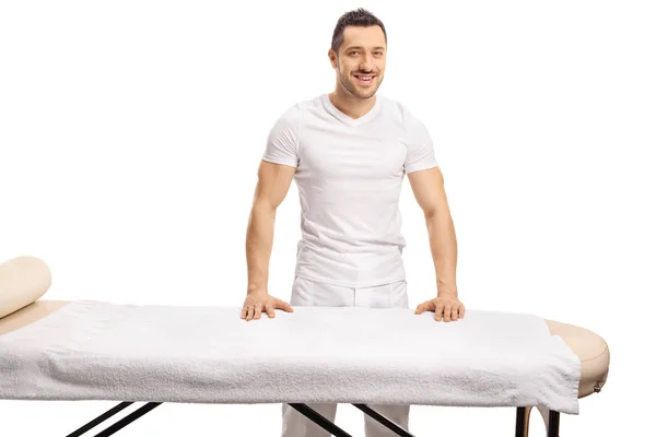 Professionale giovane massaggiatore posa dietro un letto di massaggio — Foto Stock