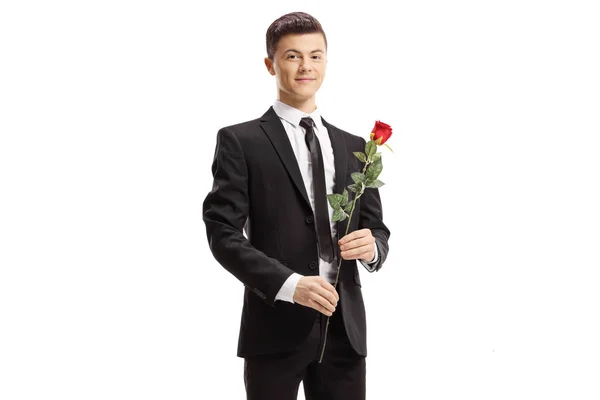 Facet w garniturze trzymając czerwoną różę i uśmiechając się do kamery — Zdjęcie stockowe