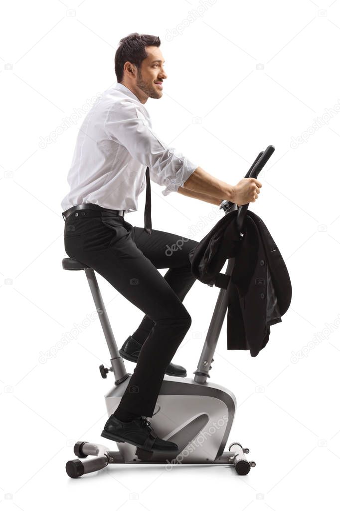 Young man in formal clothes exercising on a stationary bike