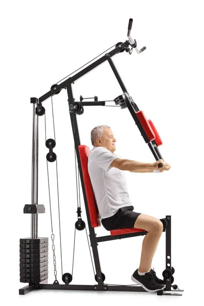 Senior man sitting on a fitness machine and exercising — Stock Photo, Image