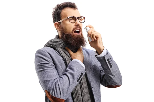 Bearded man with a sore throat spraying a medication — Stock Photo, Image