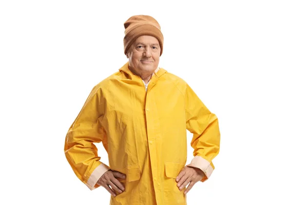 Oudere man in een gele regenjas die een warme muts draagt — Stockfoto