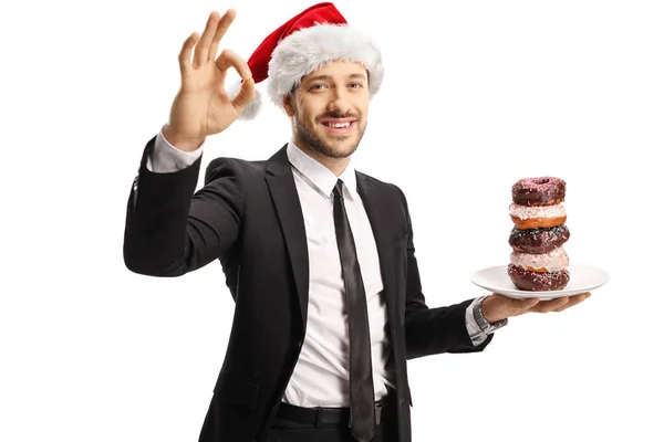 Empresario con un plato de rosquillas con un sombrero de Santa Claus y — Foto de Stock