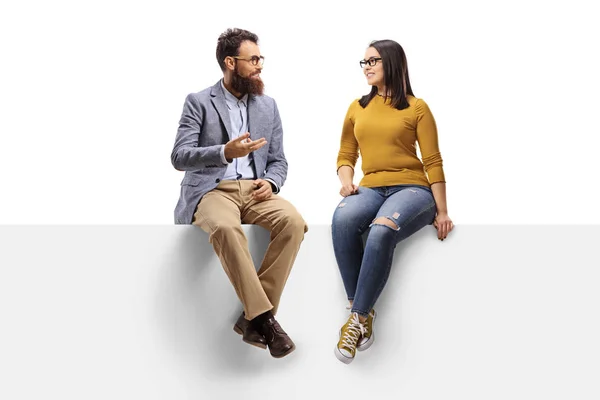 Bearded man talking to a young female seated on a banner — Stock Photo, Image