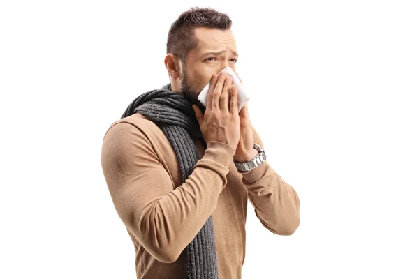 Young man with a scarf sneezing and blowing nose — ストック写真