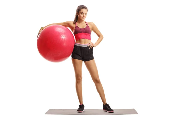 Female model posing with a fitness ball on an exercise mat — Stockfoto