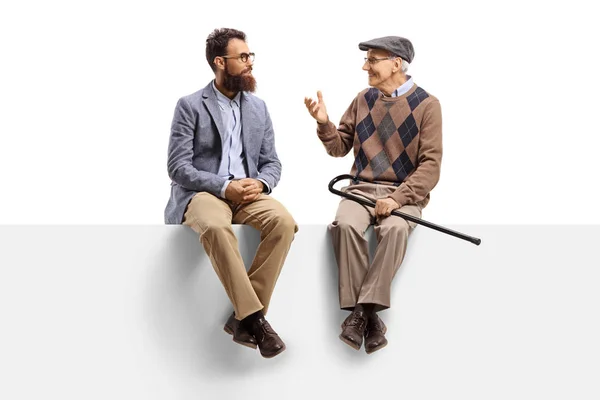 Bärtiger Mann und ein Senior, der auf einem Podium sitzt und spricht — Stockfoto