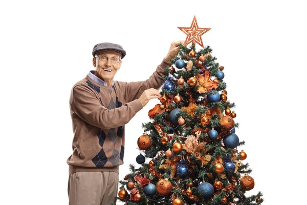 Elderly man putting a star on a Christmas tree — Stock Photo, Image