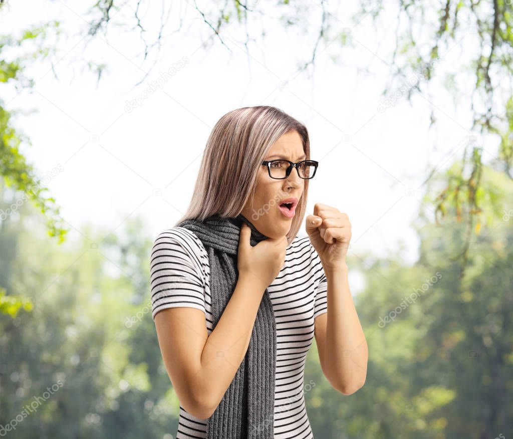 Blond female coughing and holding her throat 