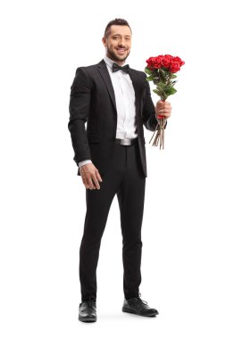 Takım elbiseli adam elinde bir demet kırmızı gül tutuyor.