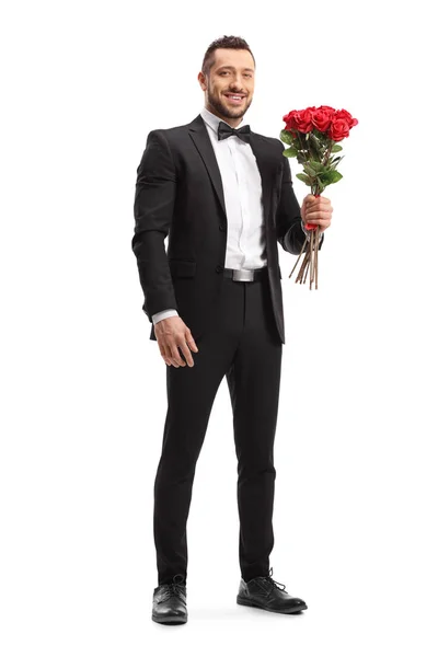 Un homme en costume tenant un bouquet de roses rouges — Photo