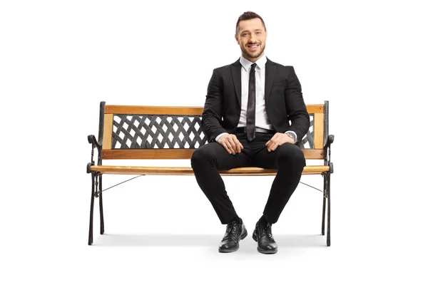 Joven hombre de negocios sentado en un banco y sonriendo — Foto de Stock