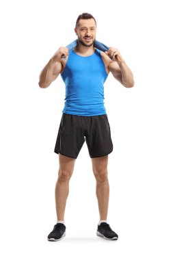 Spor kıyafetli genç kaslı bir adam boynunda bir havlu tutuyor.
