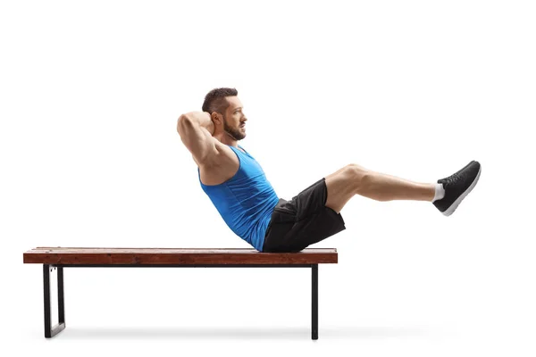 Fit jeune homme exerçant abs sur un banc — Photo