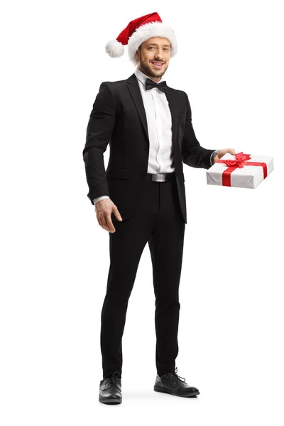 Jovem homem elegante vestindo um chapéu de Papai Noel e segurando um presente b — Fotografia de Stock