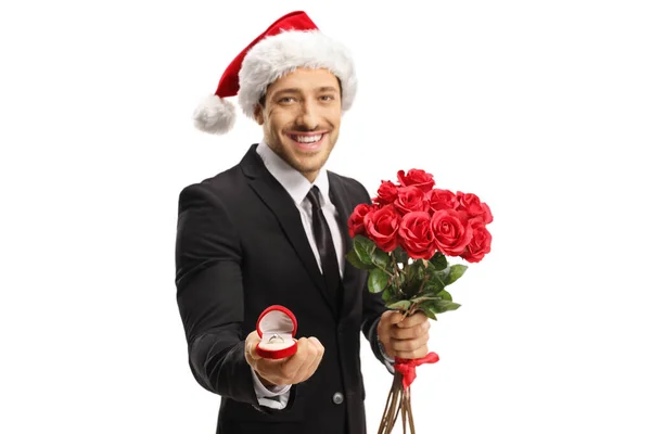 Un tizio con un cappello da Babbo Natale con un mazzo di rose e proposte — Foto Stock