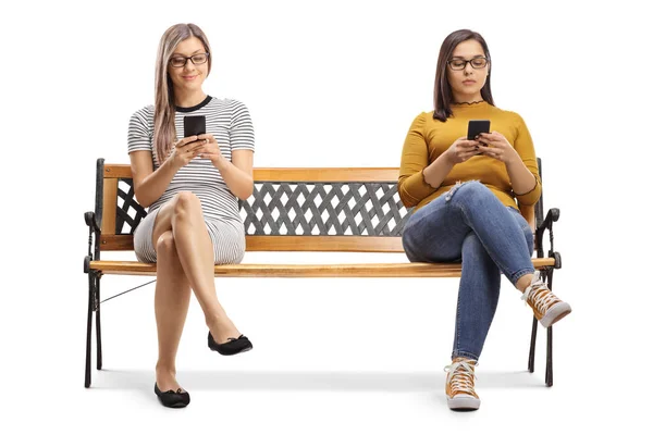 Twee jonge vrouwen zitten op een bank en typen op smartphones — Stockfoto