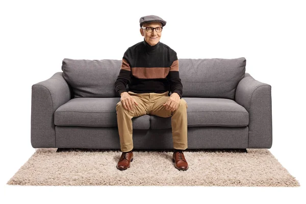 Пожилой человек сидит на диване и улыбается — стоковое фото
