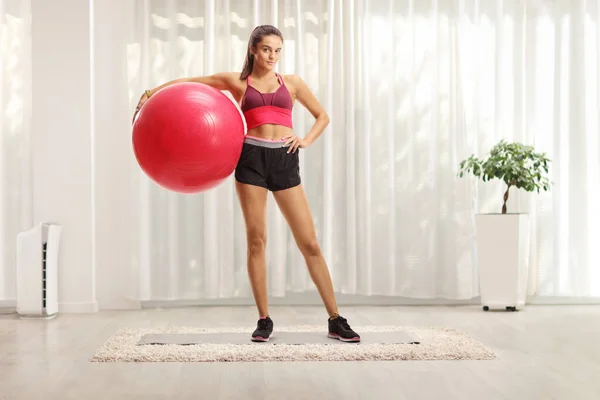 Молодая женщина позирует с фитнес-мячом дома — стоковое фото
