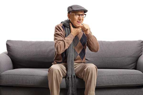 Пожилой человек, сидящий на диване и осторожно — стоковое фото