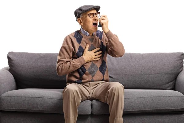 Elderly man sitting on a sofa and using an inhaler — Stock Photo, Image