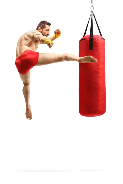 Uomo che esercita kickbox e pugni un sacco con gamba — Foto Stock
