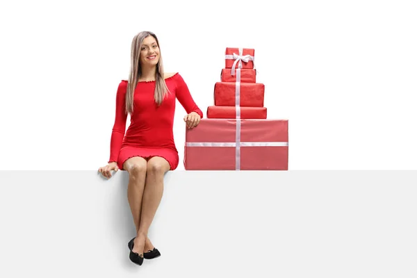 Joyeux jeune femme dans une mini robe rouge assis sur un panneau avec — Photo