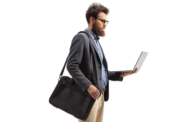 Sakallı adam omuz çantası ve dizüstü bilgisayarla ayakta duruyor. — Stok fotoğraf
