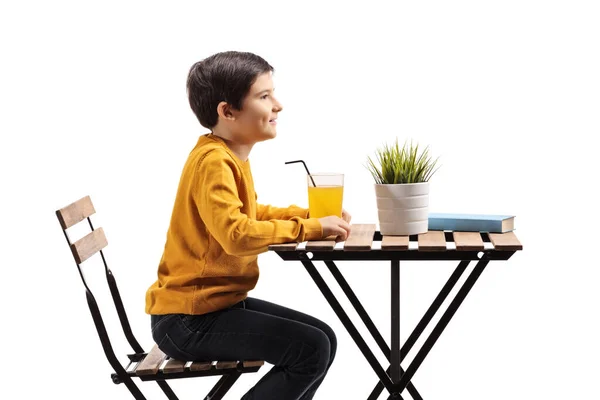 Roztomilý chlapeček sedí u stolu s pomerančovým džusem — Stock fotografie