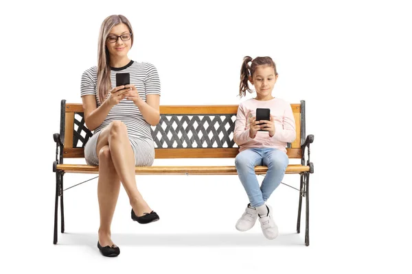 Mor och barn sitter på en bänk och använder mobiltelefoner — Stockfoto