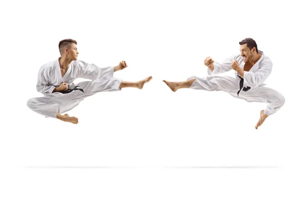 Dos jóvenes con cinturones negros en karate saltando en el aire con una k — Foto de Stock