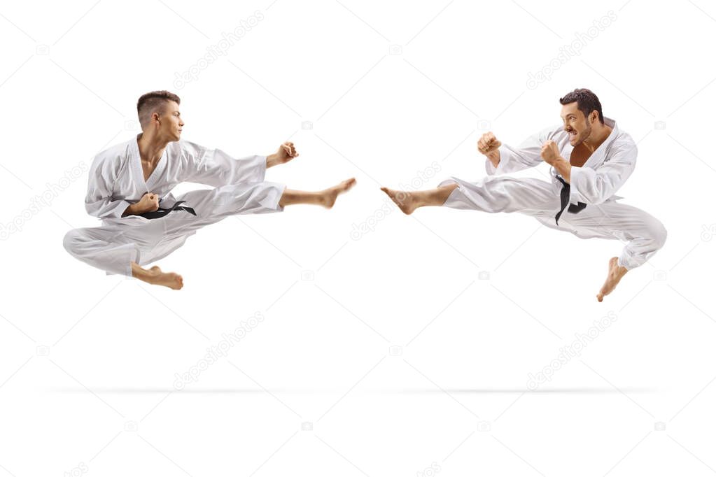 Two young men with black belts in karate jumping in air with a k