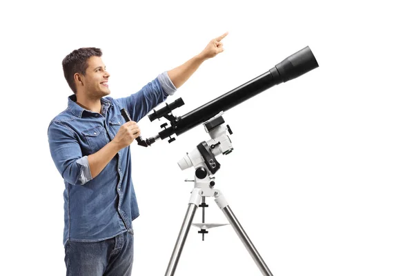 Jeune homme debout à côté d'un télescope et pointant vers le haut — Photo
