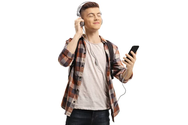 Счастливый молодой студент слушает музыку в наушниках с м — стоковое фото