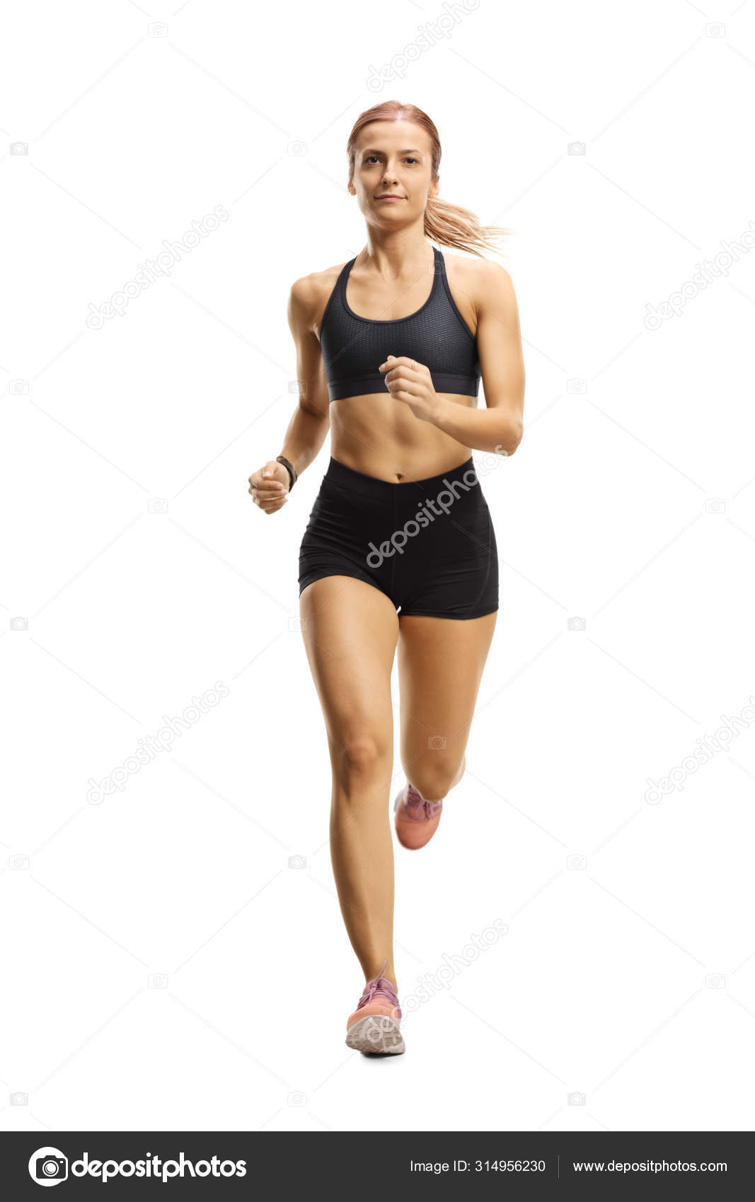 Female athlete in running outfit jogging towards the camera Stock