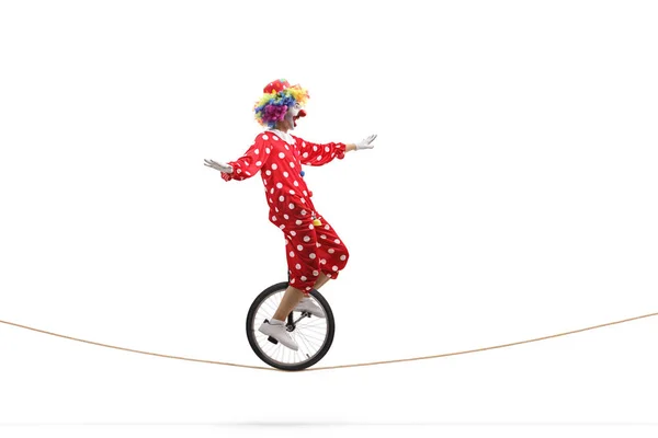 Scared clown riding a unicycle on a rope — Stock Photo, Image